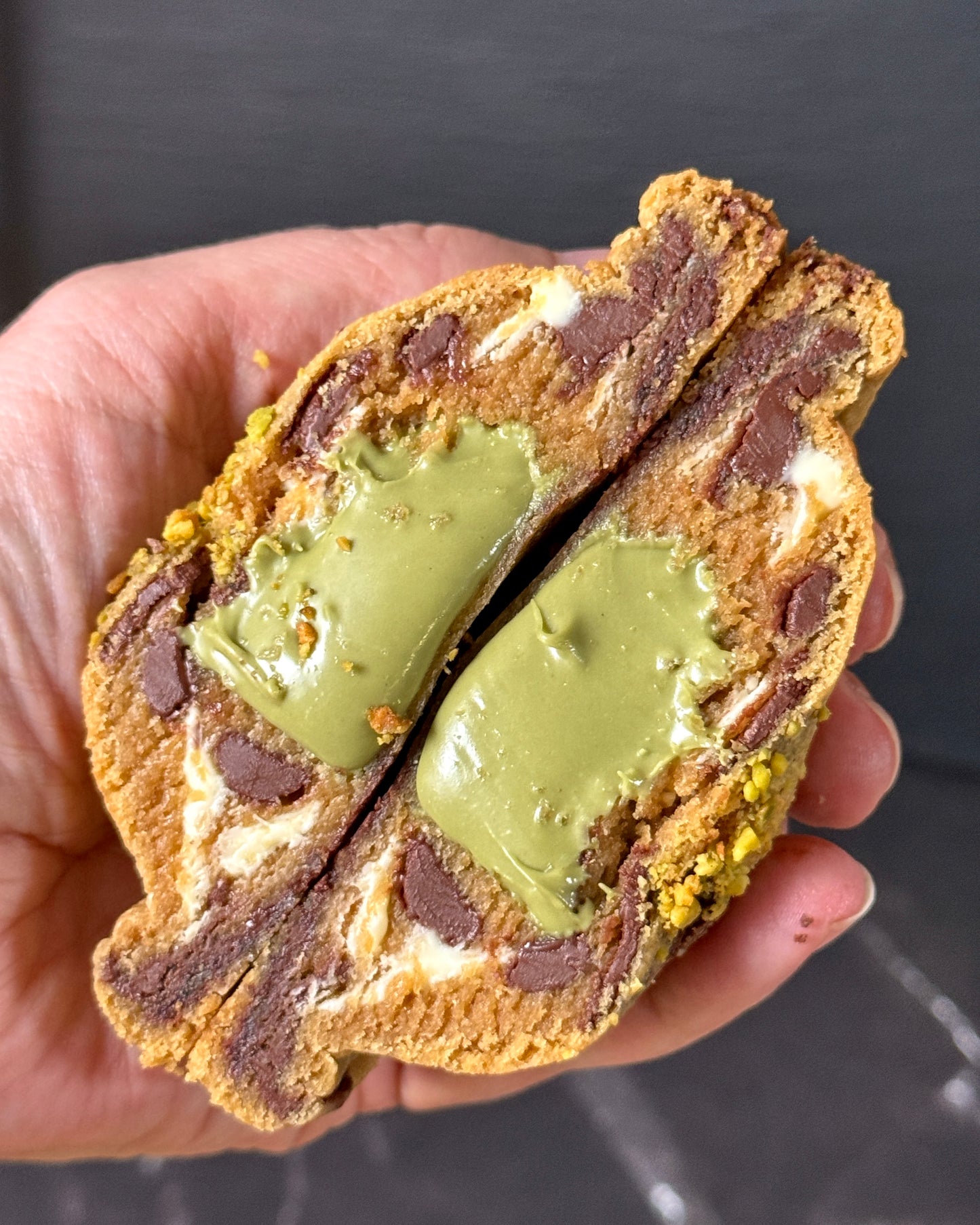 Pistachio Luxe cookie showing creamy pistachio filling with white and dark chocolate chips