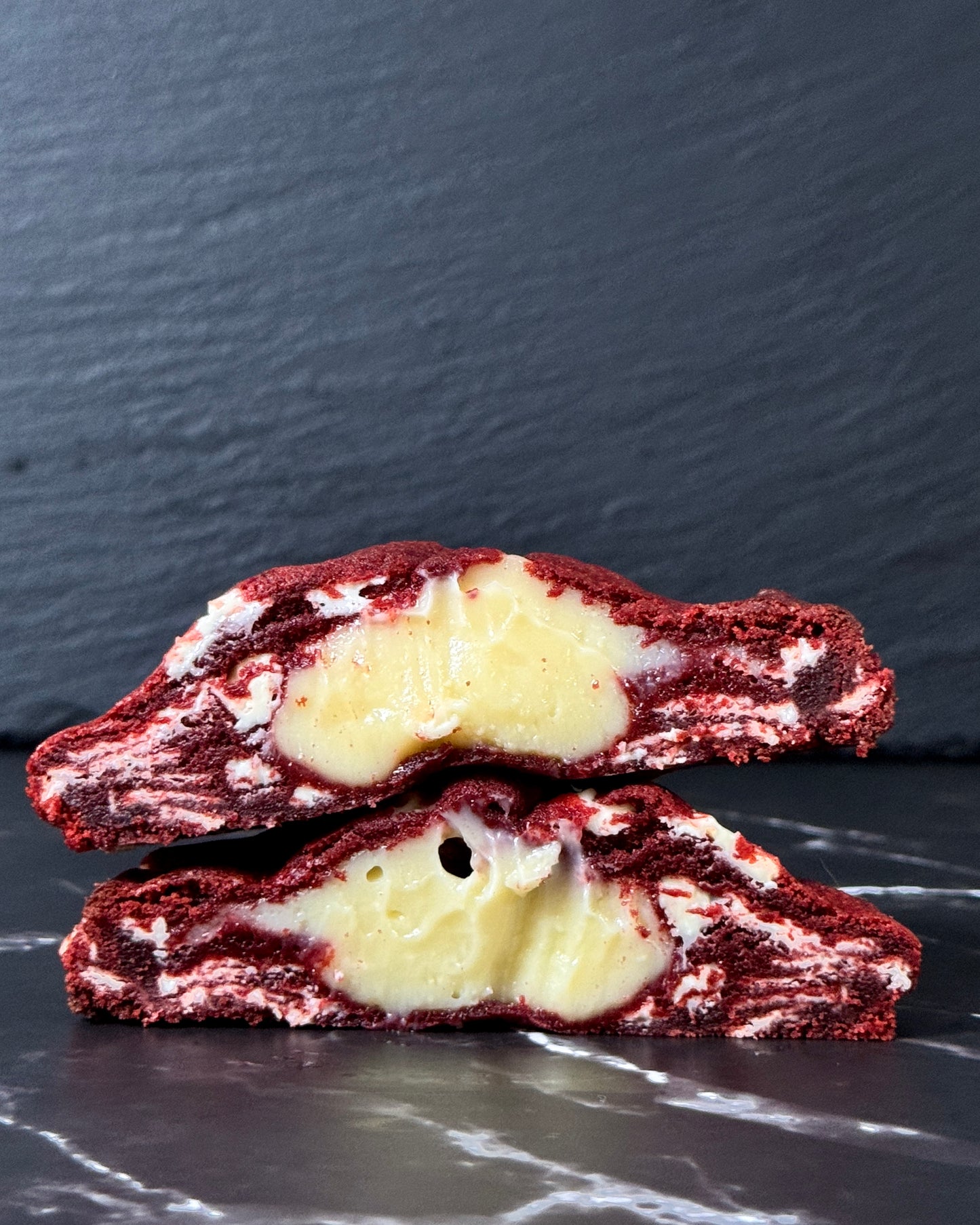 Red Velvet stuffed cookie showing smooth cheesecake centre and white chocolate chips