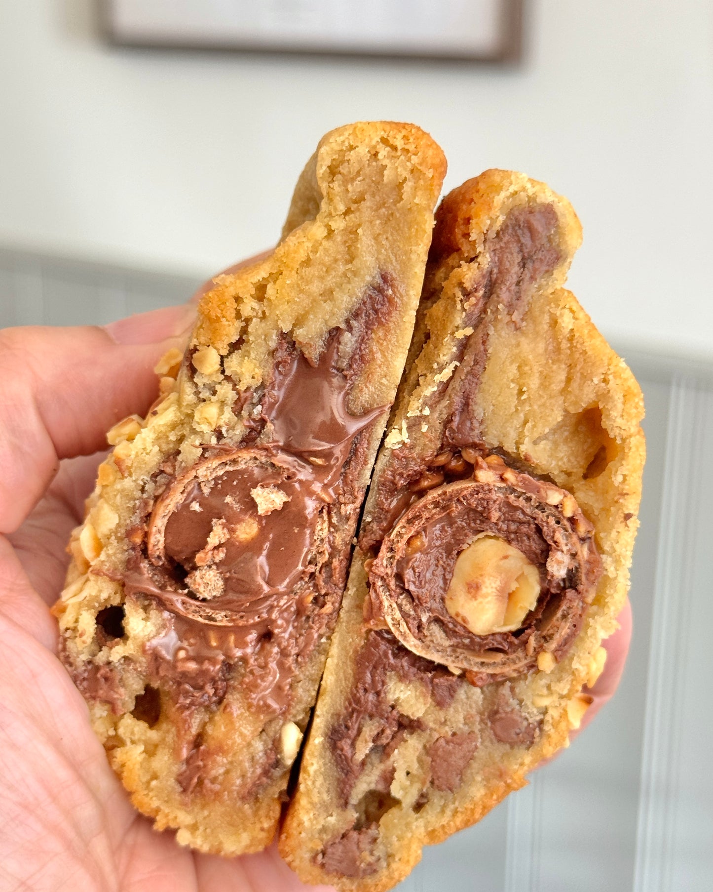 Hand holding Rocher Royale cookie showing Ferrero Rocher filling and melted hazelnut centre