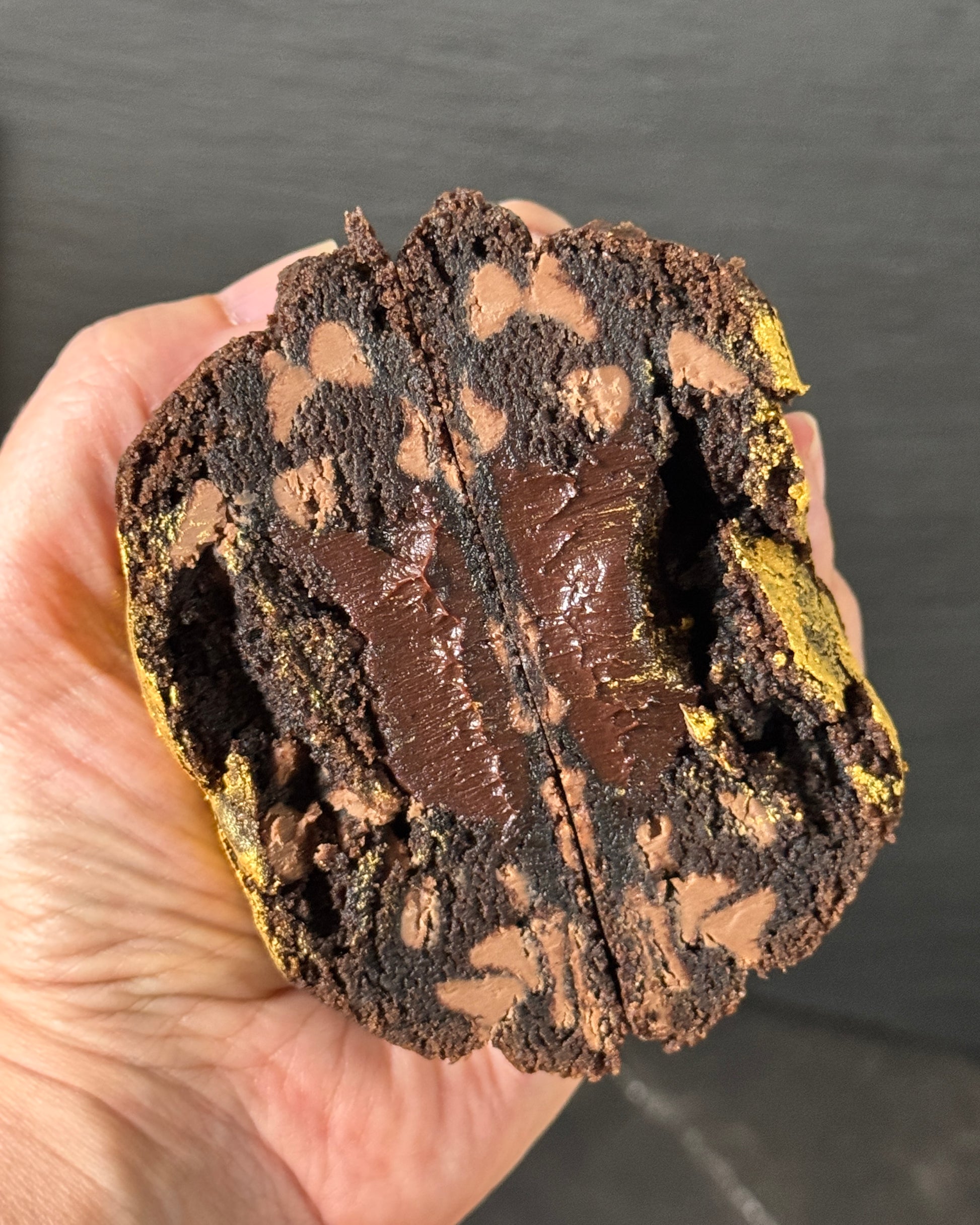 Hand holding Double Trouble NYC cookie with molten chocolate ganache filling and chocolate chunks