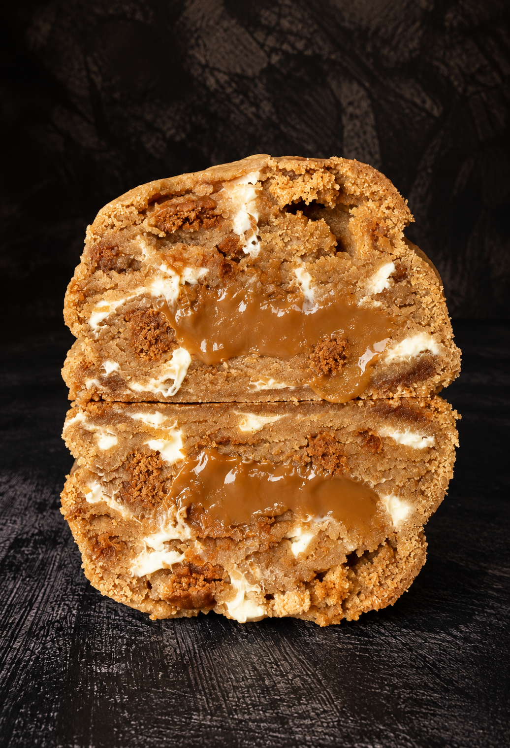 Biscoff Billionaire deep-filled cookie cut open to reveal a gooey Biscoff centre with white chocolate and Biscoff biscuit pieces, handmade in Dartmoor by Black Bird Bakers