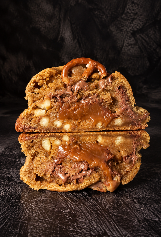 Salted Caramel Pretzel cookie cut open with a gooey caramel centre, chocolate chunks and pretzel pieces